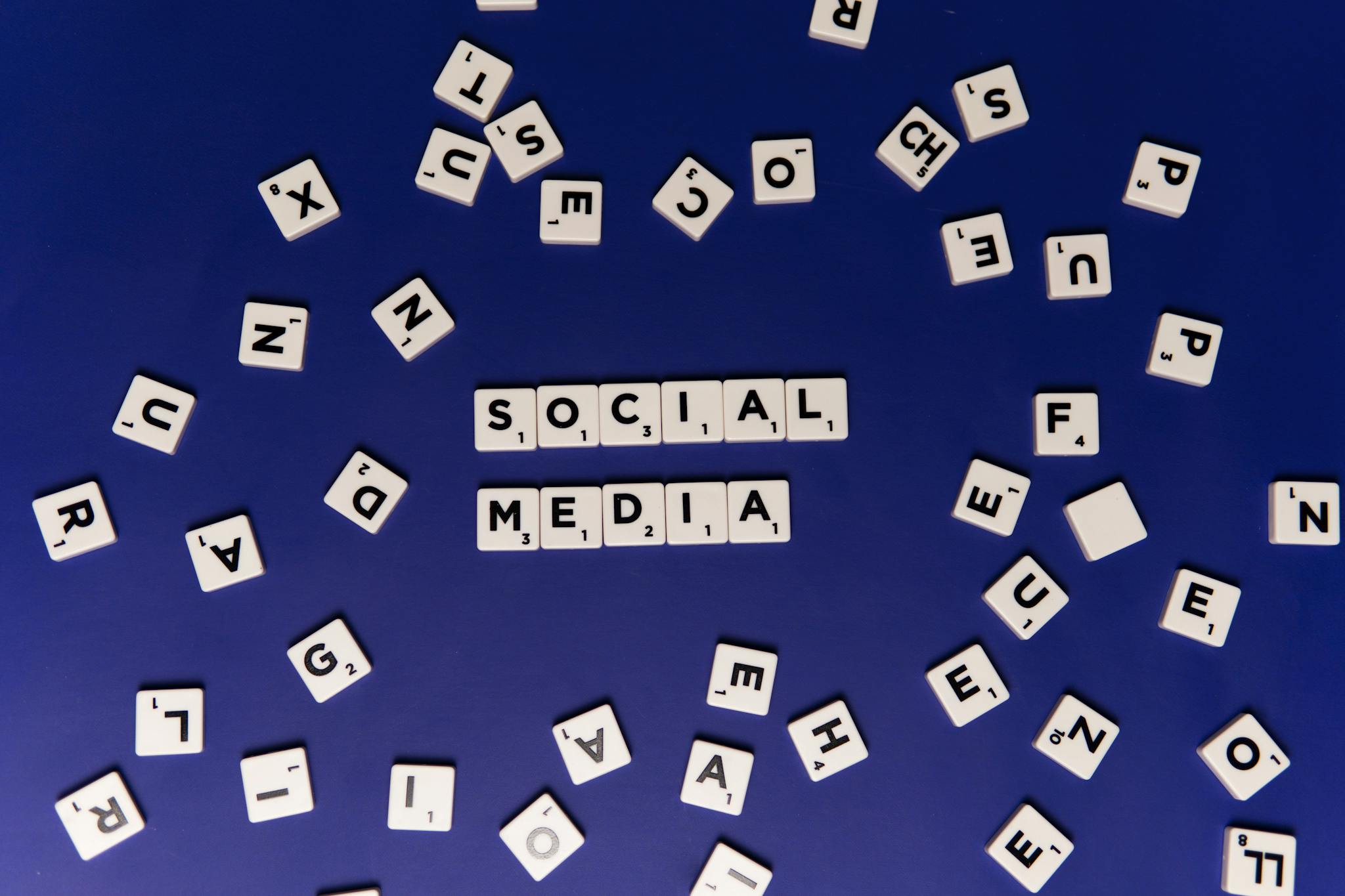 White Scrabble Blocks with Black Letters on Blue Surface